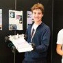 Benji holding his model in front of the display poster at the Technology Design and Innovation Challenge at Mazak thumbnail