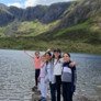 Prep-School pupils enjoying their school trip standing on the shore of a lake with mountains in the background thumbnail