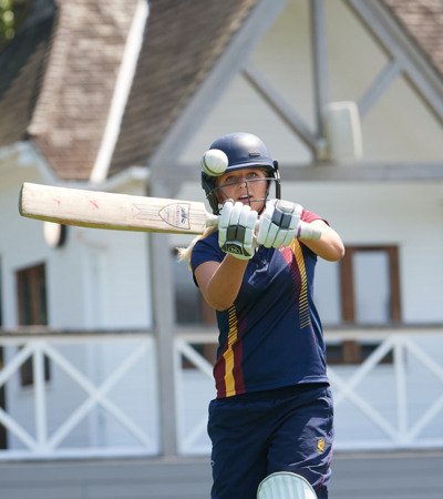 Pupil in Cricket kit hitting a cricket ball on the Home Ground in front of the Sammy Woods Pavilion