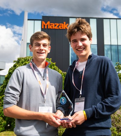 Benji and Miles in front of the Mazak building holding their Technology Design and Innovation Challenge trophy