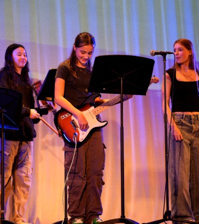 Pupils singing and playing the electric guitar on stage for Boarders Got Talent