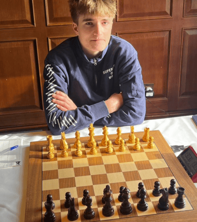 Henry sitting in front of a chess board at the Cambridge International Chess Congress