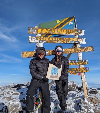 Ettiene at the top of Mount Kilimanjaro with a Brighton College tote bag raising money for charity