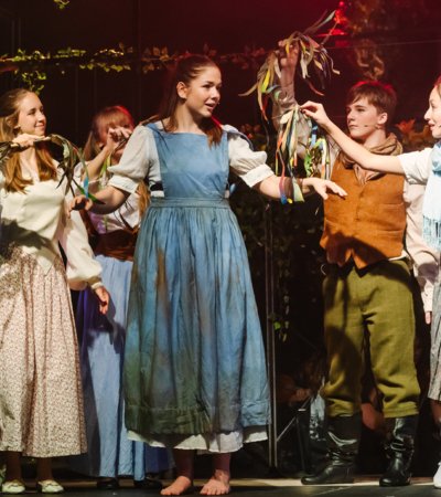 Pupils in costume on stage performing as Cinderella in the production of Into the Woods