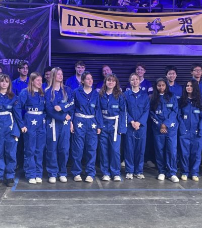 Pupils in blue boiler suits on the stage at a Robotics competition