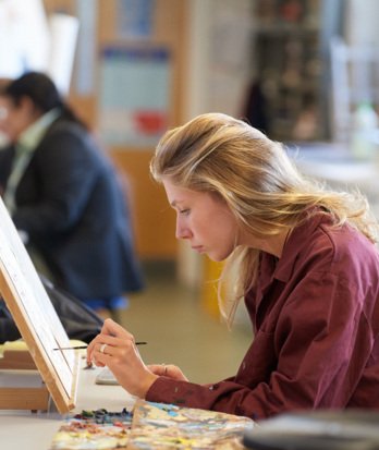 Pupil painting an A-Level coursework piece onto a canvas in the Art Room