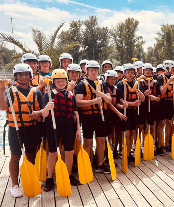 Pupils in life jackets and helmets holding paddles ready to go kayaking