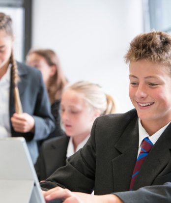 Pupils sitting in a classroom enjoying learning together on their laptops