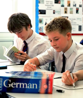 Pupils using whiteboards and dictionaries to help their learning in a German lesson