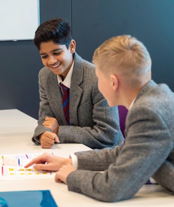 Pupils sitting together looking at a Maths book working together in a lesson