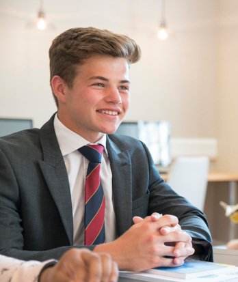 Sixth Form pupil sitting at a desk with their books enjoying a discussion with their teacher