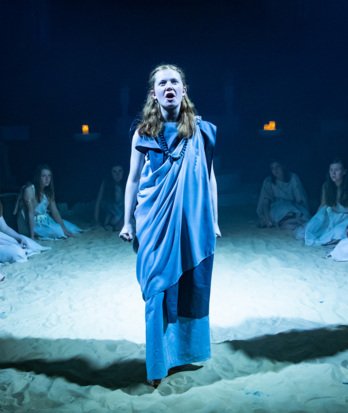 Pupils performing a re-enactment of a Greek play with the stage covered in sand