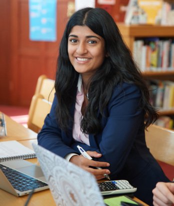 Sixth Form pupils sitting in the library with their laptop and notebook completing Maths questions