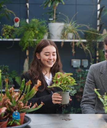 Pupils holding different plants in the Greenhouse in the SSS that they are caring for