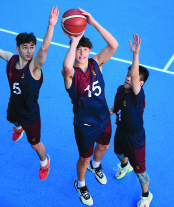 Pupil taking a shot in basketball whilst two defenders attempt to block