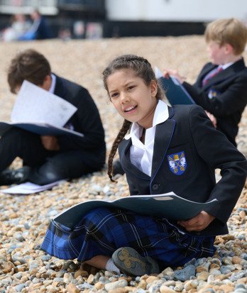 Pupils sitting on the beach with their sketchbooks drawing the view