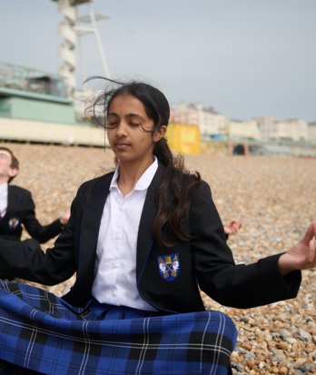 Prep School pupil sitting serenely on the Brighton Beach doing yoga