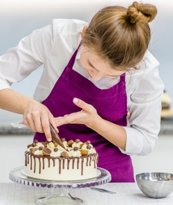 Baker holding a piping bag to decorate a cake