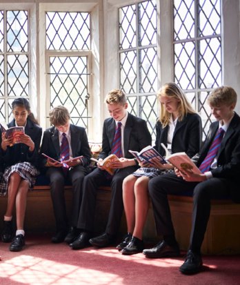 Pupils at Book club sitting on the windowsill in the library reading their books