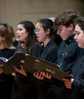 Pupils holding their sheet music and enjoying singing together with the Chamber choir in a concert