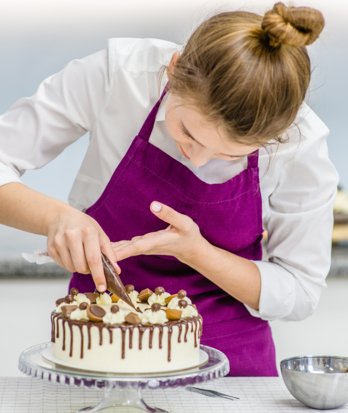 Baker holding a piping bag to decorate a cake