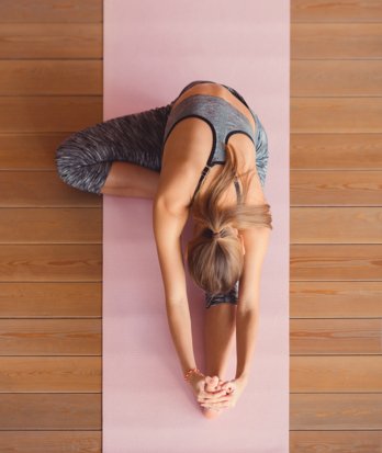 Stretching on a yoga mat in gym wear as part of a Pilates class