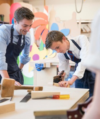 Pupil using a saw being supervised by a teacher in a Design and Technology lesson