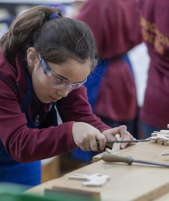 Prep School pupil in a Design Technology lesson concentrating on chiselling into their wooden creation