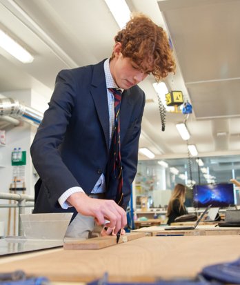 Sixth Form pupil cutting a piece of wood with a saw in an A-Level DT lesson