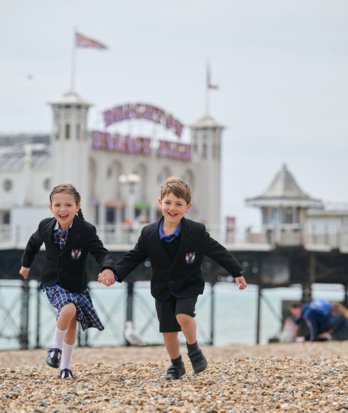 Pre-Prep pupils running along the stones on the beach in front of Brighton Pier