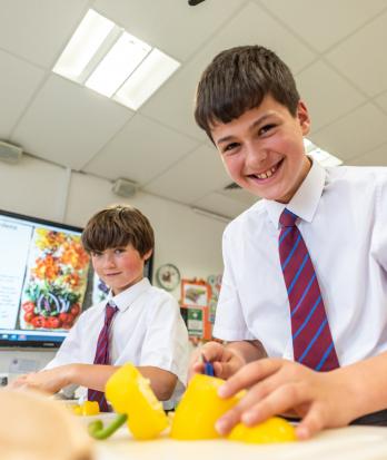 Prep School pupils in Cookery Club chopping up yellow peppers