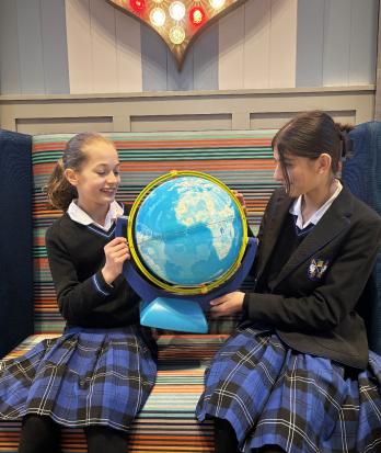 Prep School pupils looking at places on a globe in the library at Model UN Club