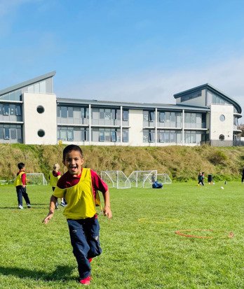 Pre-Prep pupil running across the field and enjoying Football club