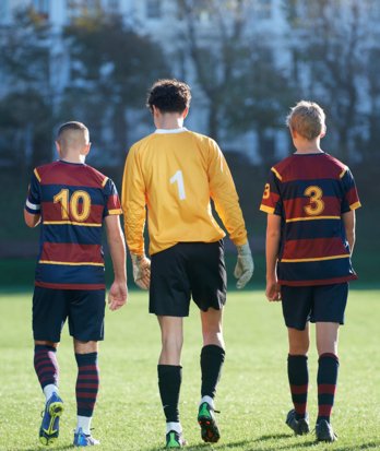 Pupils in the 1st XI Football team showing the numbers on their shirt as they walk along the Home Ground