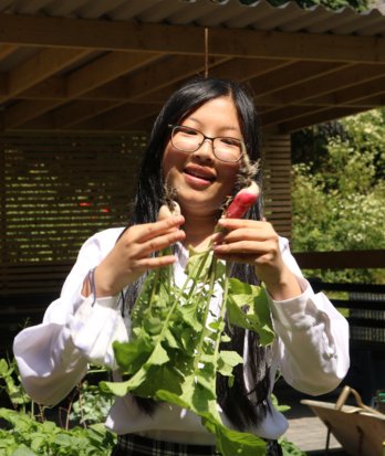 Pupil proudly admiring the produce they grew as part of Gardening Club