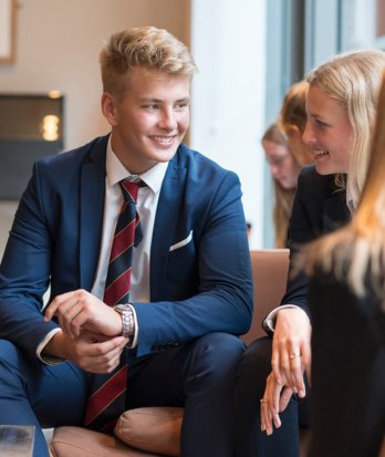 Sixth Form pupils in suits enjoying socialising on the sofas in the Smith Café