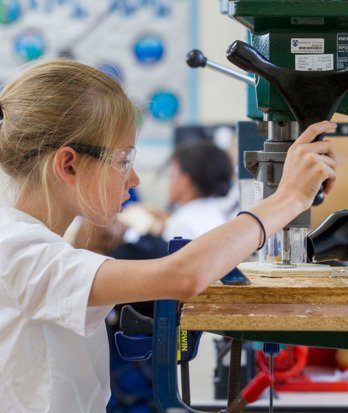 Pupil concentrating on sawing a piece of wood with a bandsaw in a DT lesson