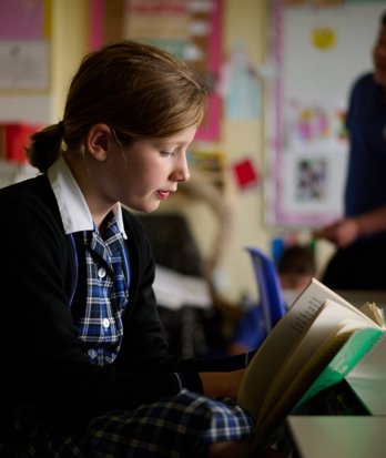 Prep School pupil reading a book in a classroom in an English lesson