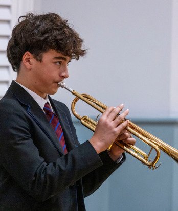 Prep School pupil playing the trumpet in a concert in the hall