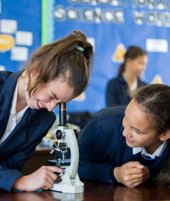 Prep School pupils in a Biology lesson looking down the lens at slides on a microscope