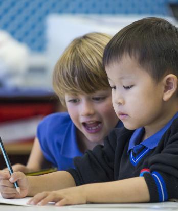 Pre-Prep pupils practicing writing in their exercises books with pencil