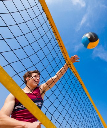 Pupil spiking the volleyball over the net on a sunny day at Yellowave