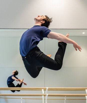 Dancer performing a C-Jump in the Studio with their reflection also visible in the mirror