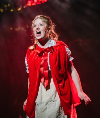 Pupil playing the part of Little Red Riding Hood on stage in the Into the Woods Production