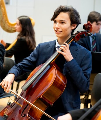 Pupil playing the cello with the orchestra as part of a concert in the Sarah Abraham Recital Hall