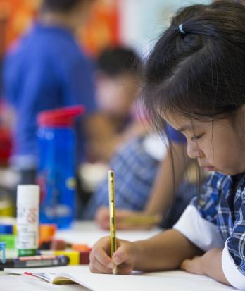 Pre-Prep pupil concentrating on writing in their exercise book with a pencil