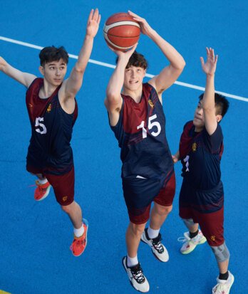 Pupil taking a shot in basketball whilst two defenders attempt to block