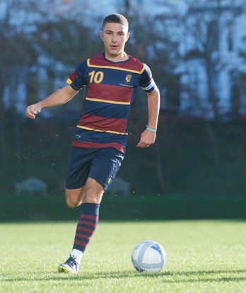 Footballer dribbling the ball along the pitch in 1st XI kit