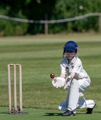 Wicket-Keeper making an excellent catch by the wickets in a Prep School cricket match