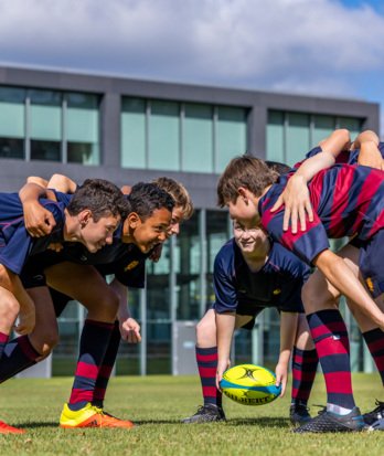 Pupils crouched into a scrum position having fun playing rugby on the Home Ground